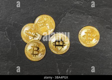 Flaches Lay-Foto - fünf goldene Bitcoin-Münzen auf schwarzem Schieferbrett - Kryptowährung Anustration, Liptovsky Hradok, Slowakei, Europa Stockfoto