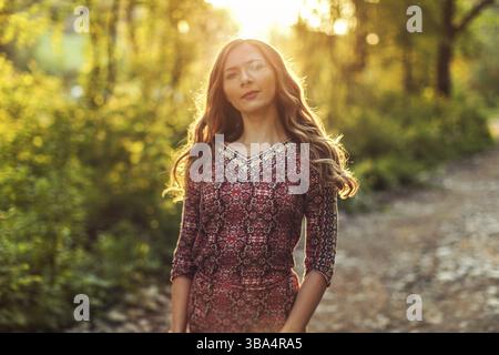 Junge Frau im Kleid, im Wald, bei Sonnenuntergang Stockfoto