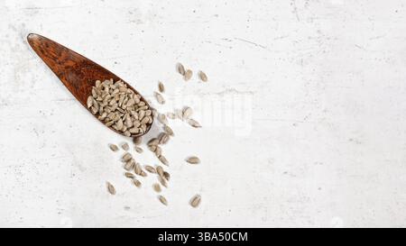 Geschälte Sonnenblumenkerne in einer kleinen Holzschaufel, auf weißem, steinähnlichem Brett platziert, Ansicht von oben, Bannerraum für Text rechts, Liptovsky Hradok, S Stockfoto