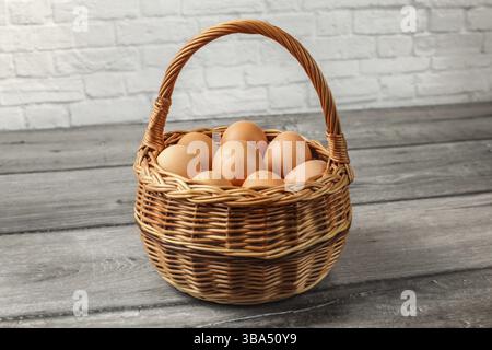 Eier in Korb, auf grauem Holztisch an der Wand Stockfoto
