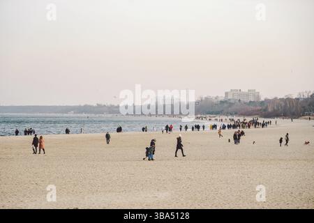 Die Leute laufen im Winter am Sandstrand. Perfekter Winterurlaub. Die Leute chillen in der kalten Jahreszeit an der Küste. Danzig, Polen, 9. Februar 2020. Wanderkrähe Stockfoto
