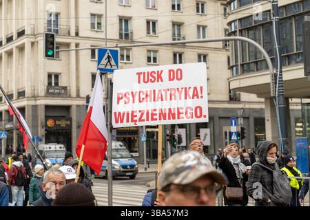 Ein Mann hält ein Anti-Donald Tusk-Plakat (polnischer Premierminister) mit der Aufschrift „Tusk to Psychiatrie“ während des Anti-Migration-marsches. Nationalistische Gruppen versammelten sich in Warschau, um an einer Demonstration mit dem Titel „Marsch gegen Migration“ teilzunehmen, die von der Grenzverteidigungsbewegung (Ruch Obrony Granic) organisiert wurde. Unter dem Motto „stoppt die Welle der Massenmigration aus fremden Kulturen“ forderte der Protest strengere Grenzkontrollen und die Deportation von Migranten ohne Papiere. Die Organisatoren kritisierten Deutschland für die Verbringung inhaftierter Migranten nach Polen. Die Teilnehmer trugen Banner und skandierten Nationali Stockfoto