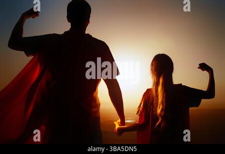 Glückliche liebevolle Familie. Vater und seine Tochter spielen draußen. Papa und sein Mädchen in einem Superhelden-Kostüme. Stockfoto