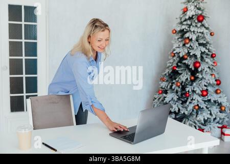 Frau am Schreibtisch mit Laptop im Büro am weihnachtsbaum Stockfoto