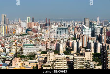Eine weitläufige Stadtlandschaft von Taipeh, Taiwan, mit dicht gepackten Wohn- und Geschäftsgebäuden, Hochhäusern und Türmen, die sich unter hellem, klarem Himmel zum Horizont hin erstrecken. Stockfoto