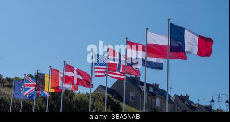 Eine Reihe von Flaggen aus verschiedenen Ländern fliegt am Himmel. Die Flaggen haben verschiedene Größen und Farben und sind in einer ordentlichen Reihe angeordnet. Konzept Stockfoto