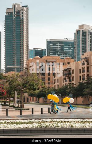 Dubai, VAE - 30. April 2025: Asiatischer Migrant Worker auf den Straßen von Dubai. Hochwertiges fotooffenes Bild eines asiatischen Arbeitsmigranten, der auf einer Straße in Dubai, Vereinigte Arabische Emirate, spaziert. In Arbeitskleidung unter der intensiven Sonne des Nahen Ostens verkleidet, repräsentiert der Mann die hart arbeitenden Einwanderer, die die rasante Stadtentwicklung der Stadt unterstützen. Das Foto zeigt Themen wie Globalisierung, Arbeitsmigration und Alltag in einer modernen Metropole. Stockfoto