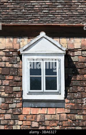 Vintage-weißes Dachfenster auf verwittertem rustikalem Terrakotta-Dach in vertikaler Form Stockfoto