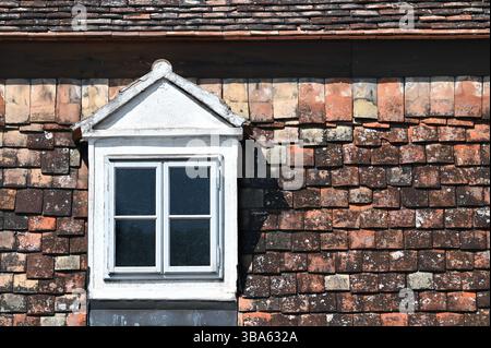 Vintage-weißes Dachfenster auf verwittertem rustikalem Terrakotta-Fliesendach Stockfoto