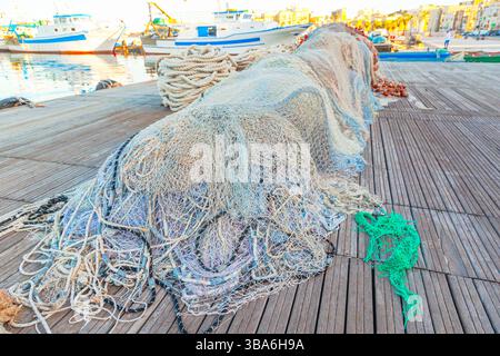 Ein großer Stapel von Fischernetzen mit Schwimmern liegt auf einem Holzsteg gesammelt. Stockfoto