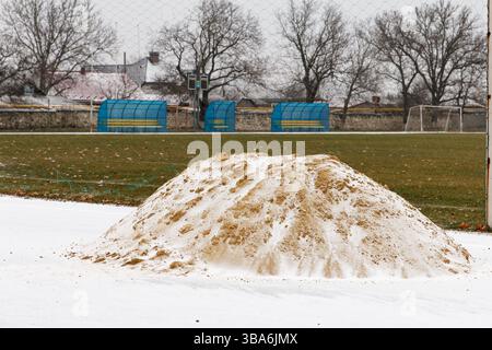 Bauarbeiten laufen. Eine Sandrutsche liegt im Winter in einem Sportstadion, bedeckt mit Schnee Stockfoto
