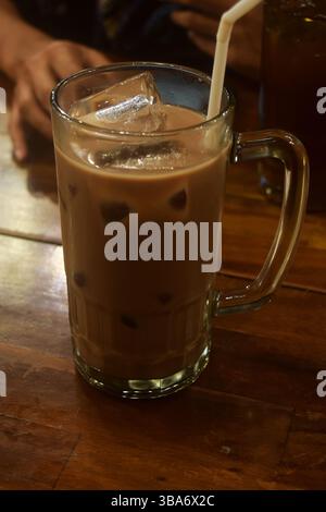 Frische Schokoladeneismilch steht auf einem Holztisch in einem Café Stockfoto