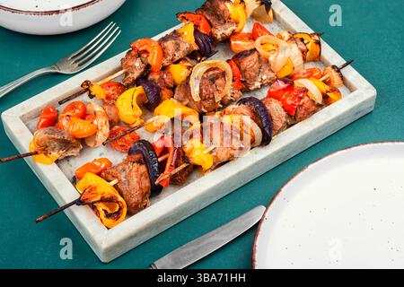 Schaschlik mit Fleisch, Kirschtomate und süßem Pfeffer. Gegrillte Fleischspieße. Das Essen wird in einem modernen Restaurant serviert. Stockfoto