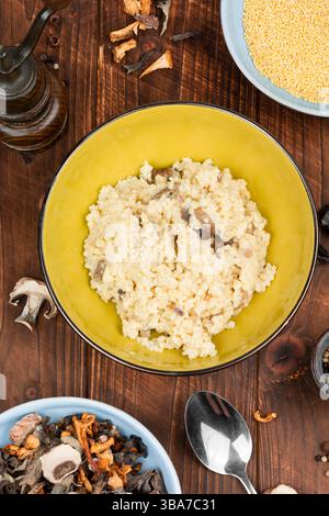 Hirsebrei mit Pilzen in einer Schüssel auf rustikalem Holzhintergrund. Gesunde Ernährung. Stockfoto