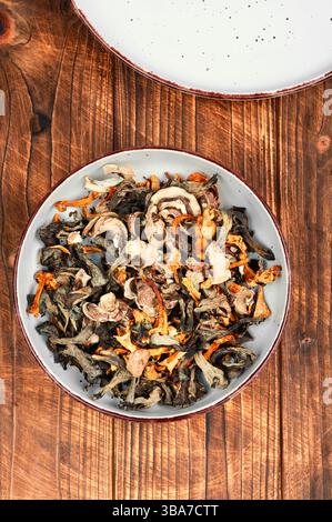 Eine lebhafte Auswahl an getrockneten Pilzen auf einem rustikalen Holztisch. Rustikaler Stil. Stockfoto