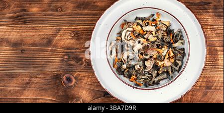 Eine lebhafte Auswahl an getrockneten Pilzen auf einem rustikalen Holztisch. Leerzeichen für Text. Stockfoto