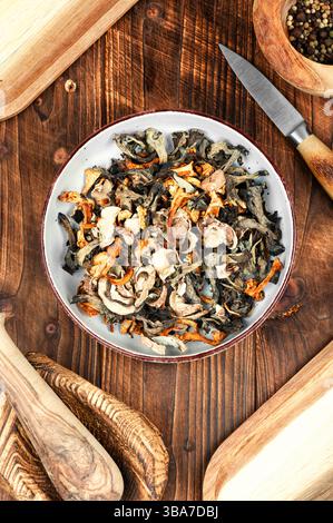 Eine lebhafte Auswahl an getrockneten Pilzen auf einem rustikalen Holztisch. Rustikaler Stil. Stockfoto