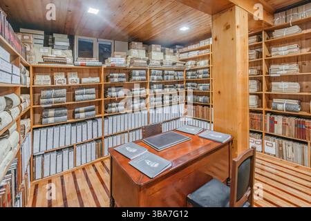 Historischer Archivraum mit Holzregalen voller Dokumente und Register. Organisierte Datensätze in einem Vintage-Speicher. Historisches Archiv von Velas, Sa Stockfoto
