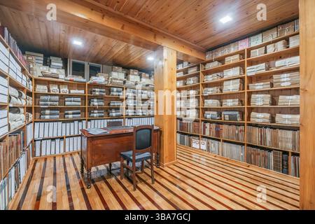 Historischer Archivraum mit Holzregalen voller Dokumente und Register. Organisierte Datensätze in einem Vintage-Speicher. Historisches Archiv von Velas, Sa Stockfoto