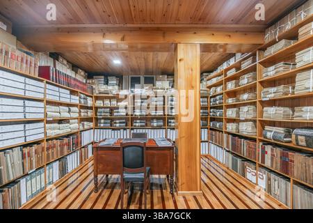 Historischer Archivraum mit Holzregalen voller Dokumente und Register. Organisierte Datensätze in einem Vintage-Speicher. Historisches Archiv von Velas, Sa Stockfoto