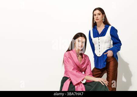 Zwei wunderschöne junge Zwillingsschwestern posieren elegant, während sie ihren modischen Stil feiern. Stockfoto