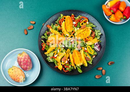 Köstlicher veganer Salat aus Kaktusfrüchten, heißen Paprika, grünen Blättern und Mandeln. Israelische Küche. Flache Lagen. Stockfoto