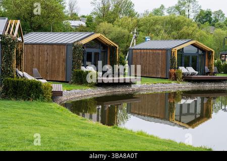 Holzhütten am See spiegeln sich in ruhigem Wasser, eingebettet in üppiges Grün. Stockfoto