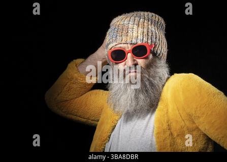 Kreativer älterer Mann mit grauem Bart in modischer Kleidung auf schwarzem Hintergrund Stockfoto