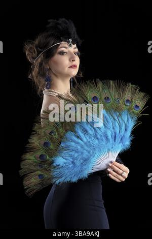 Retro-Porträt einer Frau. Schönes Mädchen mit einem Fan im Stil der 20er oder 30er Jahre Altmodisches Fingerwellen-Make-up und Friseur Stockfoto