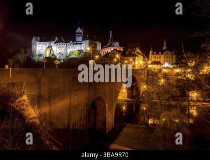 Nächtlicher Blick auf eine Stadt Loket und Schloss Loket (Hrad Loket, Burg Elbogen), uneinnehmbare Burg auf einem massiven Felsen, beleuchtet von Straßenlaternen. Touristen-spo Stockfoto