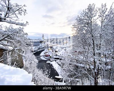 cesky Krumlov, UNESCO. Historische Stadt mit Schloss und Kirche bei Sonnenaufgang. Wunderschöne Winterlandschaft am Morgen mit einem beleuchteten Denkmal. Schneebedeckter Zick Stockfoto