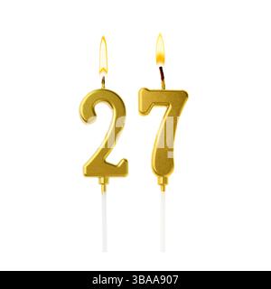 Brennende goldene Kuchenkerzen, die Nummer 27 auf weißem Hintergrund bilden. Festliche Dekoration zum Geburtstag oder zu einem anderen besonderen Datum Stockfoto