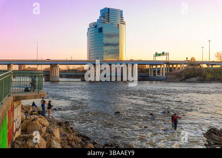 Grand Rapids, MI, USA - 23.04.2025: Foto von Menschen, die am Fluss in Grand Rapids Michigan angeln und entspannen während des Sonnenuntergangs mit malerischer Aussicht und Kal Stockfoto
