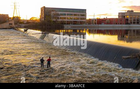 Grand Rapids, MI, USA - 23.04.2025: Foto von Menschen, die am Fluss in Grand Rapids Michigan angeln und entspannen während des Sonnenuntergangs mit malerischer Aussicht und Kal Stockfoto