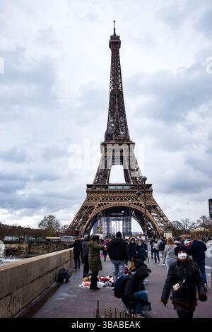 Paris, Frankreich - 4. Dezember 2021: Bürgersteig unter dem Eiffelturm an einem dunklen, bewölkten, regnerischen Herbsttag in Paris, Frankreich. Stockfoto