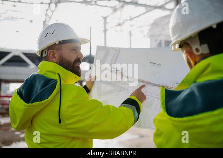 Bauleiter, die vor Ort ein digitales Tablet verwenden, um Projektpläne zu überprüfen. Stockfoto
