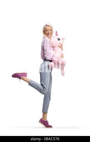 Glückliche Frau, die ein großes Einhornspielzeug auf weißem Hintergrund hält Stockfoto