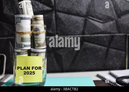 Konzept des Plans für 2025 Schreiben Sie auf Haftnotizen mit Dollar in Glasgefäß Stockfoto