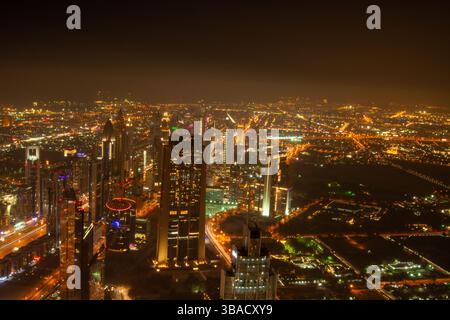 Ein atemberaubender Blick aus der Luft auf die pulsierende Skyline der Stadt bei Nacht mit beleuchteten Wolkenkratzern und belebten Straßen. Die Szene fängt das Wesen von ein Stockfoto