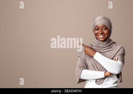 Aktivieren Sie Diese Option. Lächelnde Afrikanische Muslimische Lady Zeigt Auf Copy Space Mit Finger Stockfoto