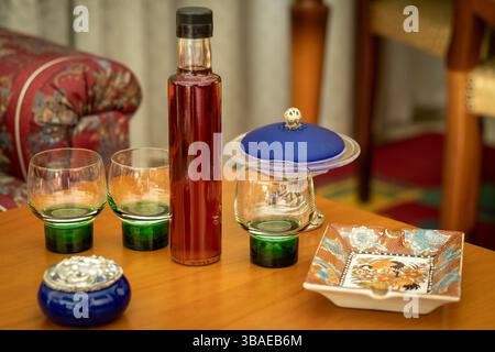 Eine Flasche Alkohol und Gläser, die auf einem kleinen Tisch serviert werden können. Stockfoto