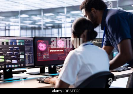 Der afroamerikanische Ingenieur im Server-Hub half dem Manager bei der Untersuchung von Sicherheitswarnungen, um Geräte vor Hackern zu schützen. Mitarbeiter, der Hilfe vom Vorgesetzten anfordert, um Sicherheitsrisiken zu mindern Stockfoto