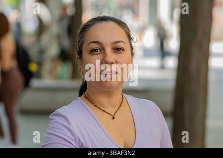 Eine 40-45-jährige, moderne Erwachsene Frau in einer städtischen Umgebung, die in die Linse schaut Stockfoto