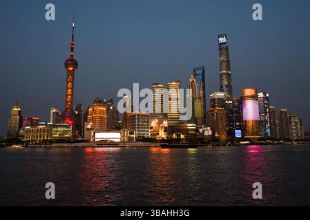 Shanghai, China - 1. April 2025: Abendlicher Blick auf die Skyline von Pudong vom Bund mit dem Oriental Pearl Tower und Shanghai Tower beleuchtet vor dem Dämmerhimmel Stockfoto