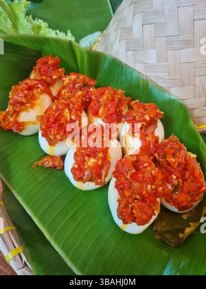 Telur Balado oder gekochte Eier mit rotem Chili Sambal Balado, indonesisches Minangkabau Padang Essen aus West Sumatra, serviert auf einem Bananenblatt Stockfoto