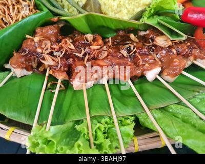 Indonesische Sate Ayam oder Chicken Satay Spieße mit Erdnusssoße und serviert auf einem Bananenblatt Stockfoto