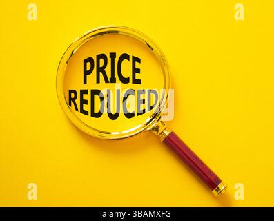 Symbol für reduzierte Preise. Lupe mit Konzeptwort Preis reduziert. Schöner gelber Hintergrund. Business- und preisreduziertes Konzept. Kopierbereich Stockfoto