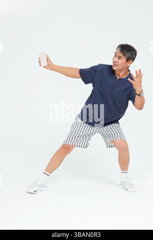Ein alter Mann lächelt, während er ein Handy-Selfie macht Stockfoto