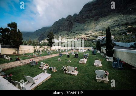 Ruhiger Friedhof, eingebettet in dramatische Berge und üppige Bananenplantagen Stockfoto