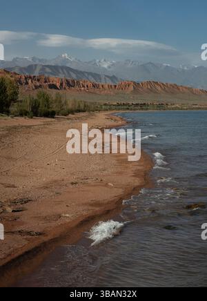 Malerischer Blick auf Sandstein und schneebedeckte Berge vom Ufer des Issyk-Kul Sees Stockfoto